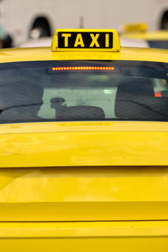 Leistungsspektrum Close-up of a yellow taxi in Athens, Greece, highlighting the bright sign and urban setting.